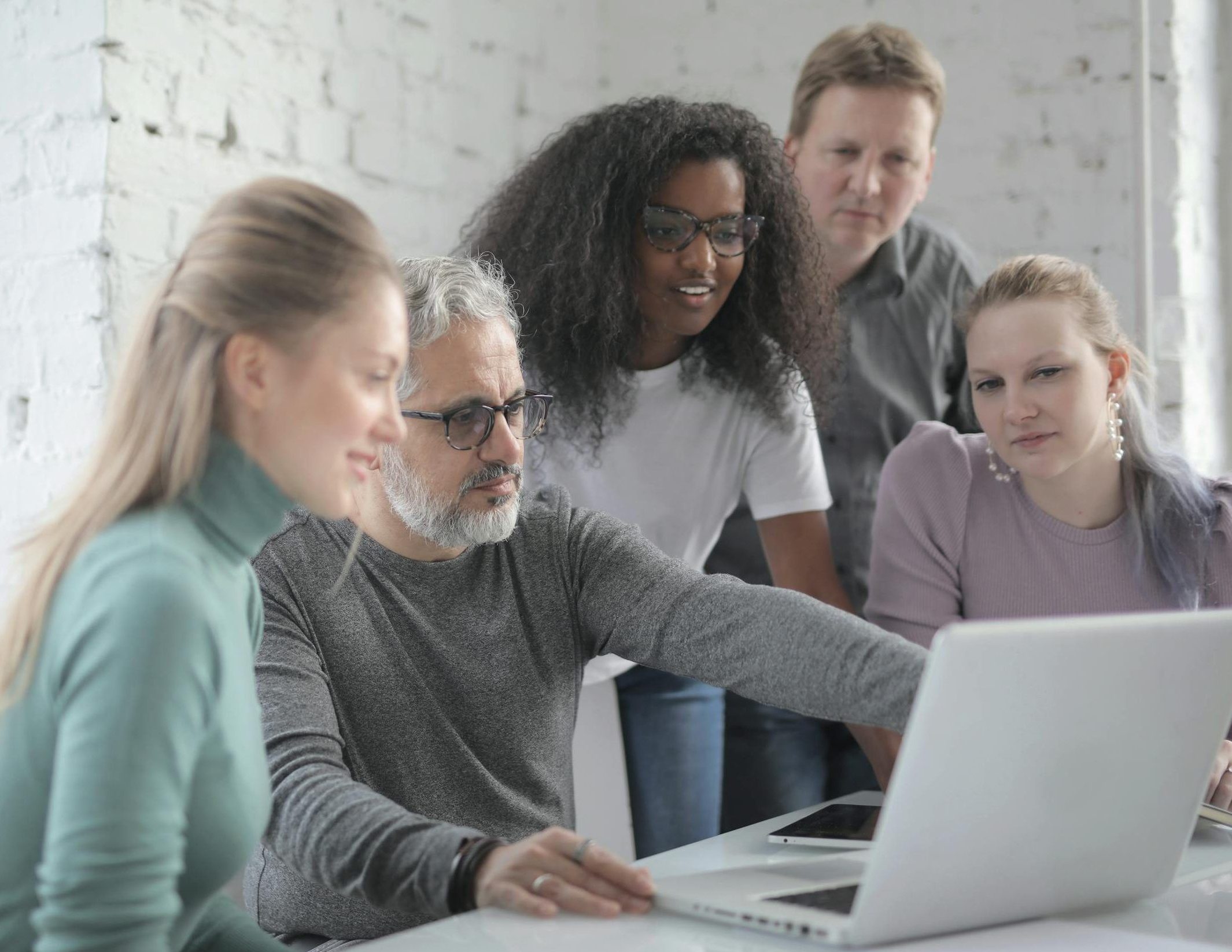 A diverse group of colleagues collaborating around a laptop at work.